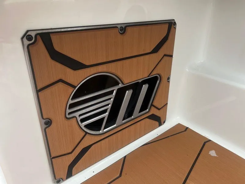 Slide: The Image of 2025 Malibu 23 MXZ boat interior with stylish wood paneling and logo design. - 14