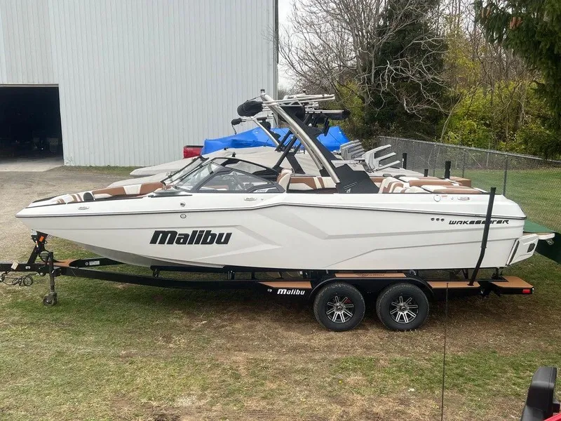 Slide: The Image of 2025 Malibu 23 MXZ boat on trailer, parked outdoors near a building. - 3