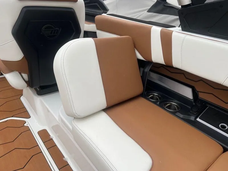 Slide: The Image of 2025 Malibu 23 MXZ boat interior with brown and white seating, cup holders, and sleek design. - 8