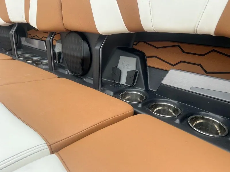 Slide: The Image of 2025 Malibu 23 MXZ interior with tan and white seats, cup holders, and speaker. - 9