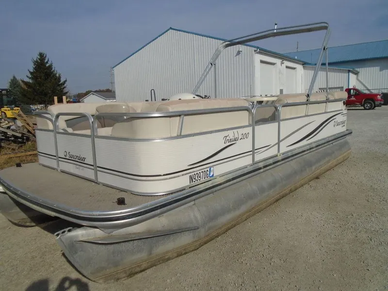 Slide: The Image of 2005 Lowe Trinidad 200 pontoon boat parked on gravel near metal buildings. - 2