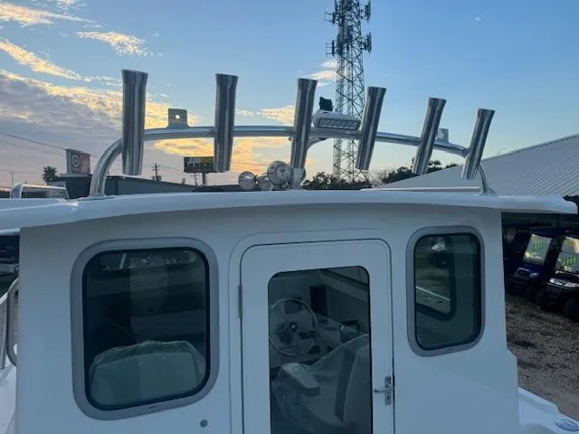 Slide: The Image of 2025 Parker 2420 Sport Cabin boat with rod holders, against a sunset sky. - 13