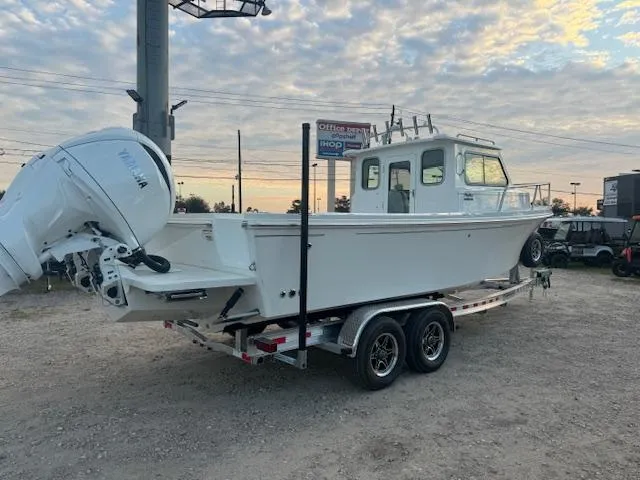 Slide: The Image of 2025 Parker 2420 Sport Cabin boat on trailer under cloudy sky. - 2