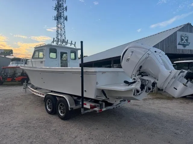 Slide: The Image of 2025 Parker 2420 Sport Cabin boat on trailer, parked outdoors near a building. - 3