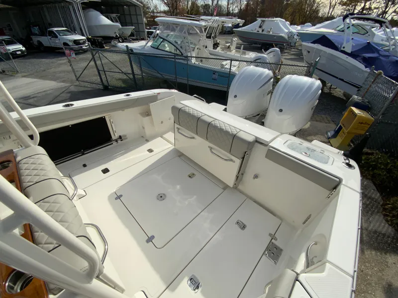 Slide: The Image of 2025 Pursuit S 288 Sport boat deck with dual engines in a marina setting. - 17