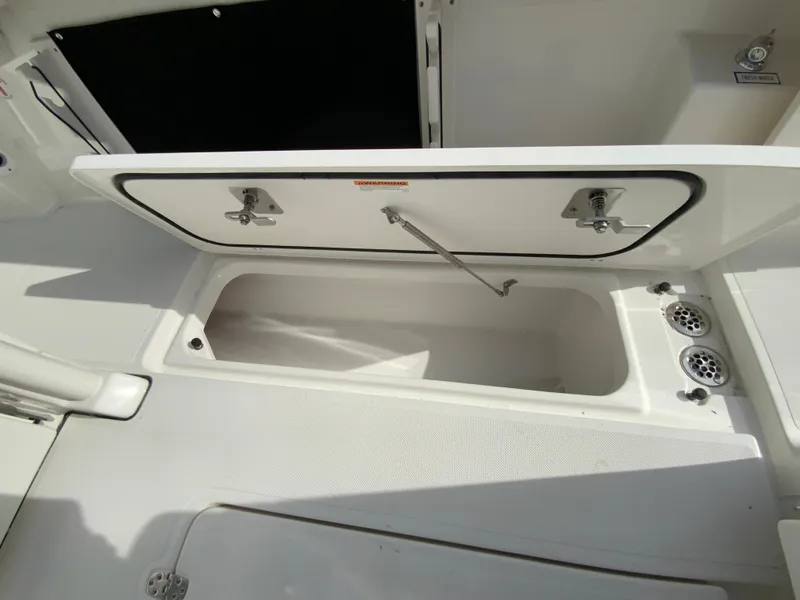 Slide: The Image of 2025 Pursuit S 288 Sport boat storage compartment open, showcasing spacious interior. - 24