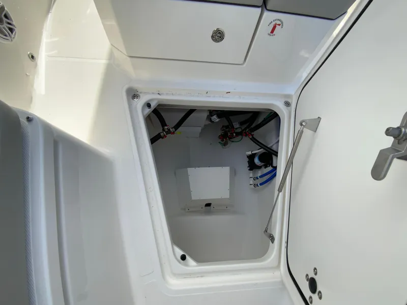 Slide: The Image of 2025 Pursuit S 288 Sport boat storage compartment with visible wiring and plumbing. - 35