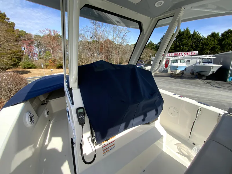 Slide: The Image of 2025 Pursuit S 288 Sport boat interior with covered console, parked outdoors. - 40