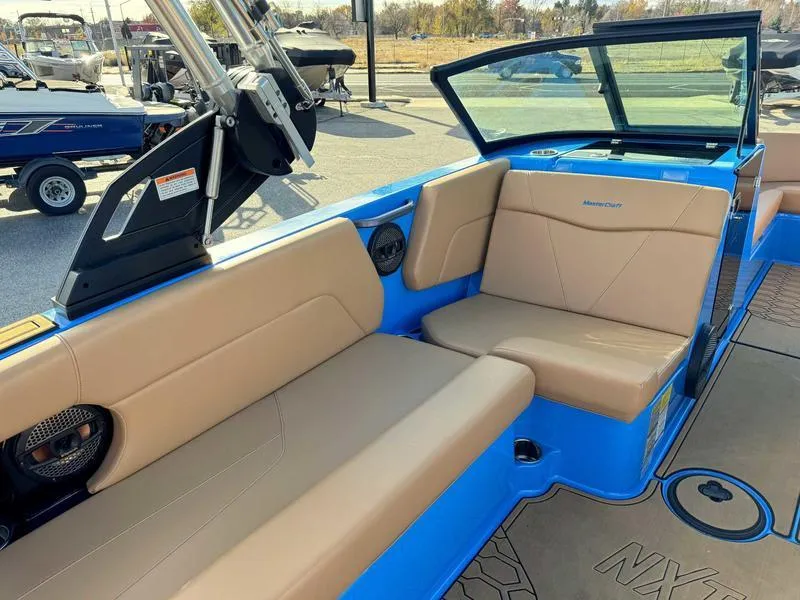 Slide: The Image of 2024 MasterCraft NXT23 boat interior with tan seating and blue accents. - 10