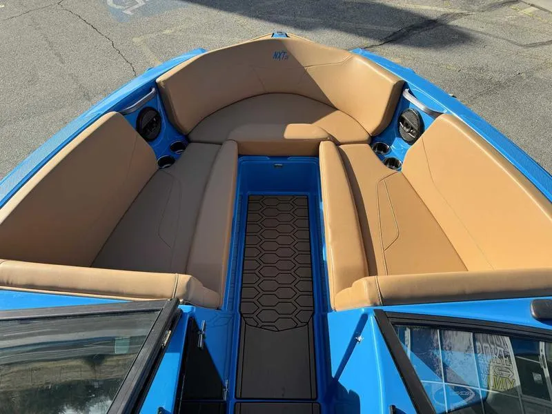 Slide: The Image of 2024 MasterCraft NXT23 boat interior with tan seating and blue accents. - 13