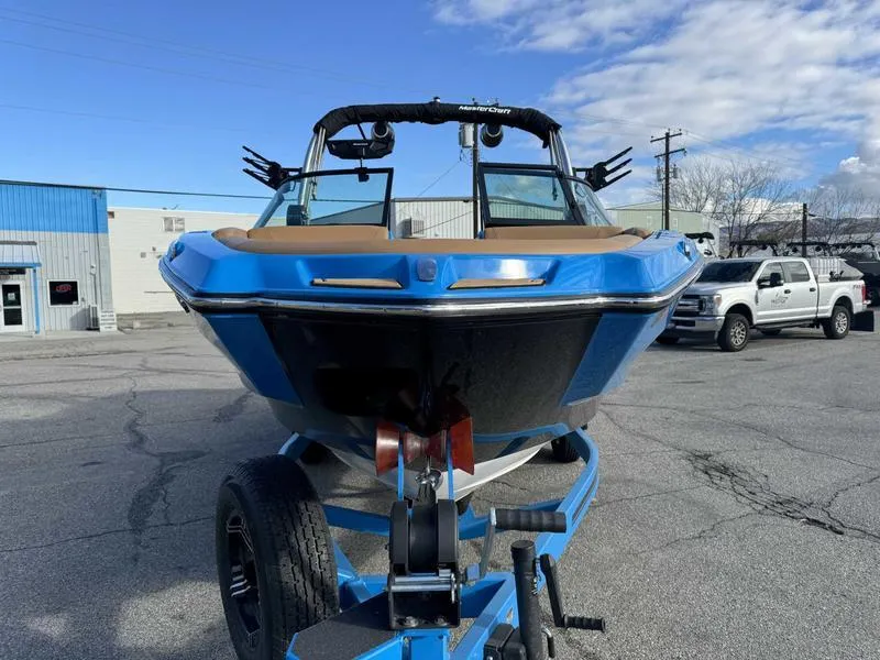 Slide: The Image of 2024 MasterCraft NXT23 boat on trailer, blue and black design, parked outdoors. - 4