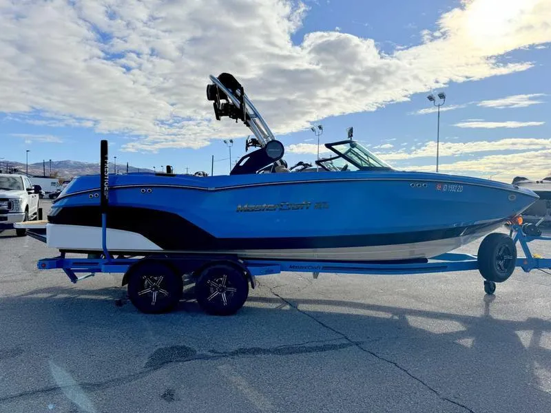 Slide: The Image of 2024 MasterCraft NXT23 boat on trailer under a partly cloudy sky. - 5