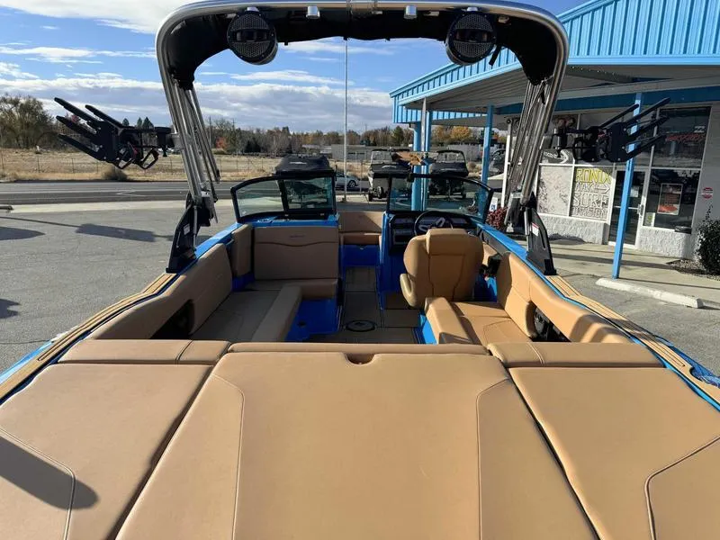 Slide: The Image of 2024 MasterCraft NXT23 boat with tan interior and blue accents, parked outdoors. - 8