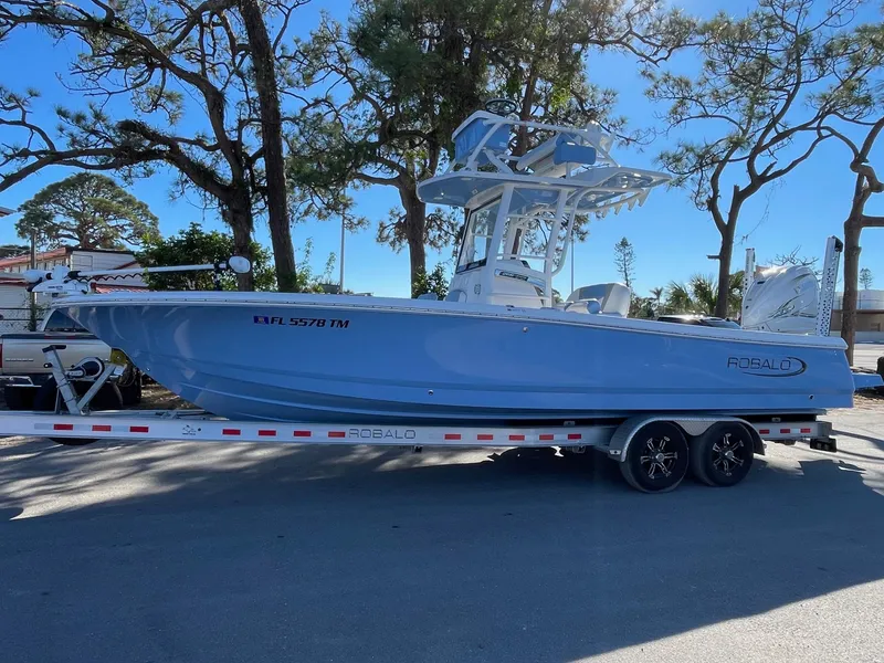 Slide: The Image of 2023 Robalo 266 Cayman SD boat on trailer, parked outdoors. - 1