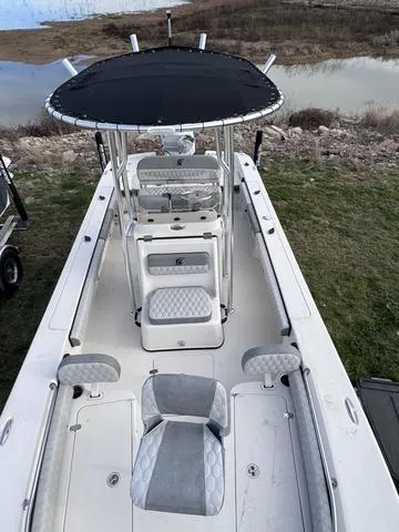 Slide: The Image of 2025 Carolina Skiff 22 Ultra Elite boat with seating and canopy, parked near water. - 9