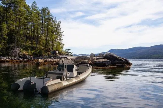 Slide: The Image of Arksen 8 boat, 2025 model, anchored near rocky shoreline and forested landscape. - 7
