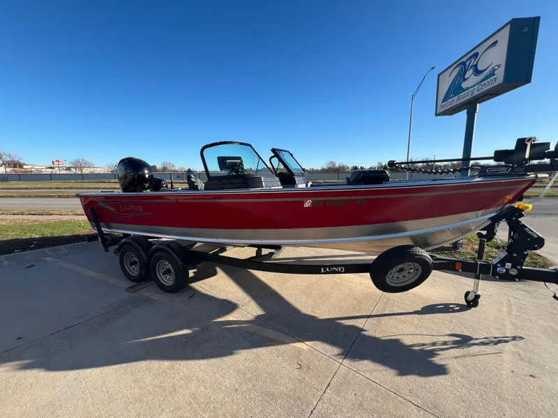 Slide: The Image of 2024 Lund 2075 Alaskan Sport boat on trailer, red exterior, parked outdoors. - 3