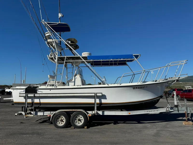 Slide: The Image of 1997 Shamrock 260 Open boat on trailer, featuring blue canopy and fishing equipment. - 11