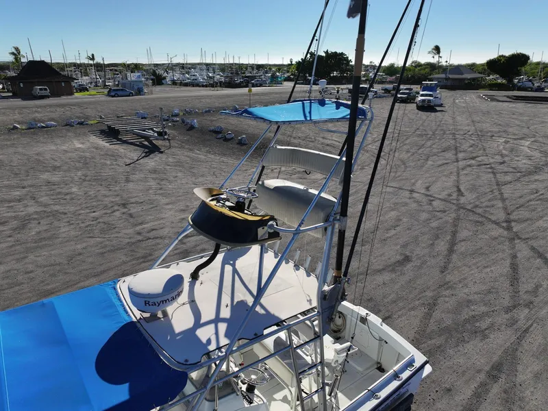 Slide: The Image of 1997 Shamrock 260 Open boat with blue canopy in a marina parking area. - 21