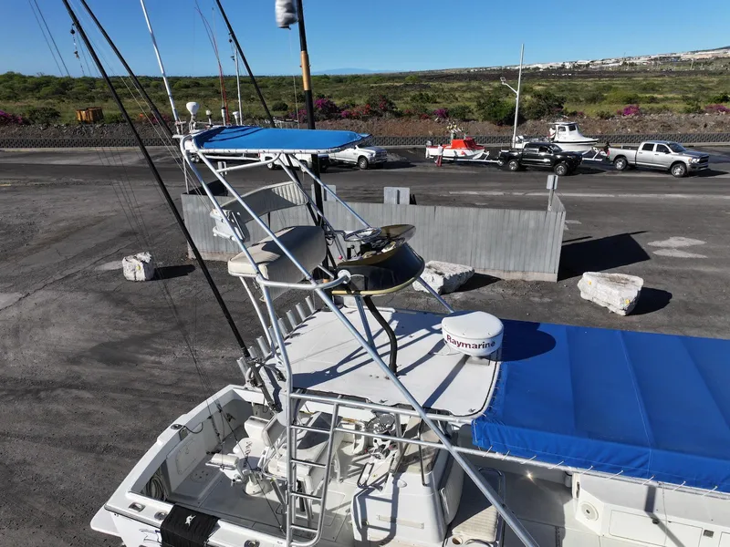 Slide: The Image of 1997 Shamrock 260 Open boat with blue canopy and fishing equipment at a dock. - 22