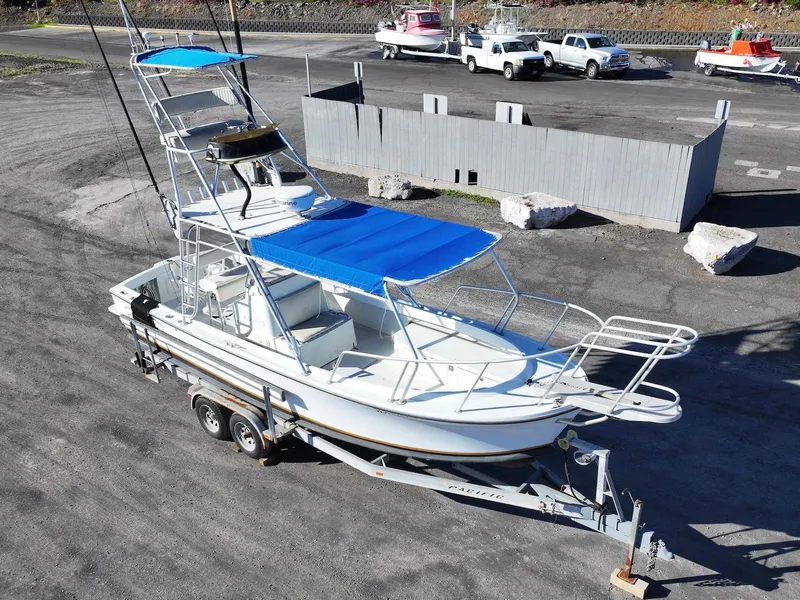 Slide: The Image of 1997 Shamrock 260 Open boat with blue canopy on a trailer in a parking lot. - 6