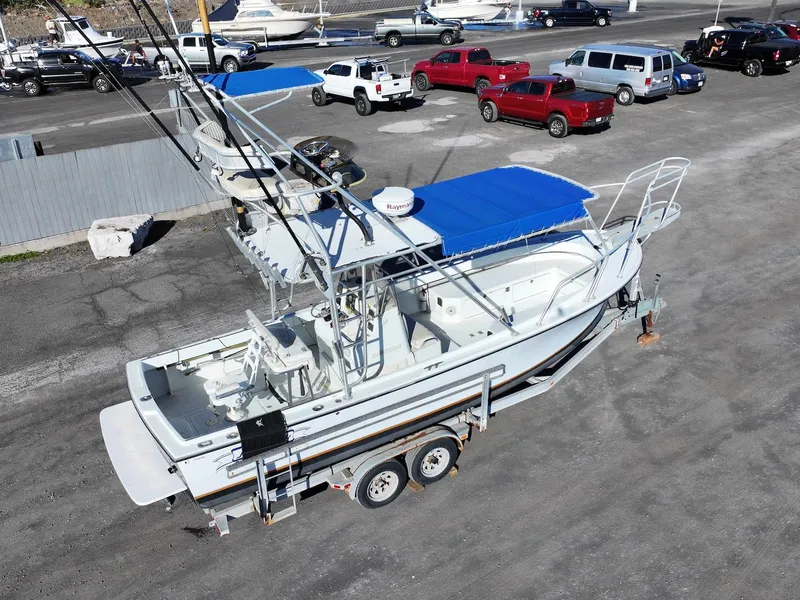 Slide: The Image of 1997 Shamrock 260 Open boat on trailer, blue canopy, parked in lot. - 8