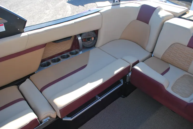 Slide: The Image of 2023 MasterCraft X24 interior with beige and maroon seating, cup holders, and speaker system. - 14