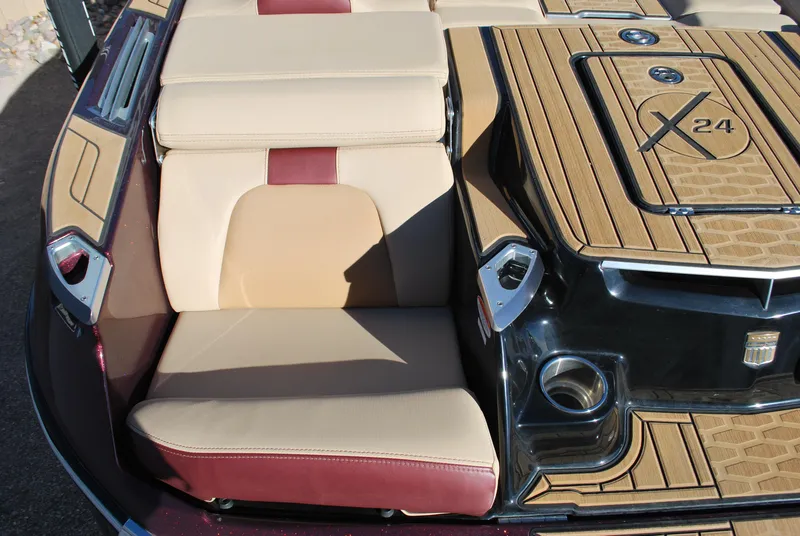 Slide: The Image of 2023 MasterCraft X24 boat interior with tan and red seating, teak flooring. - 17