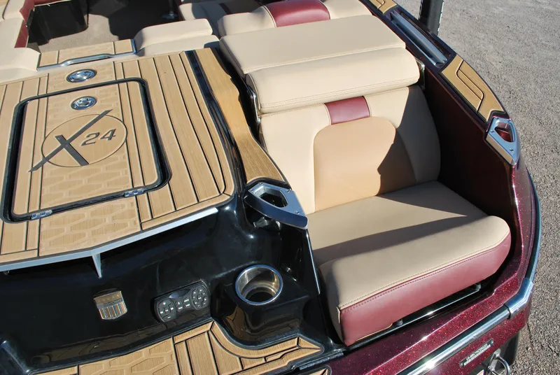 Slide: The Image of 2023 MasterCraft X24 boat interior with beige and maroon seating, cup holder, and deck details. - 18