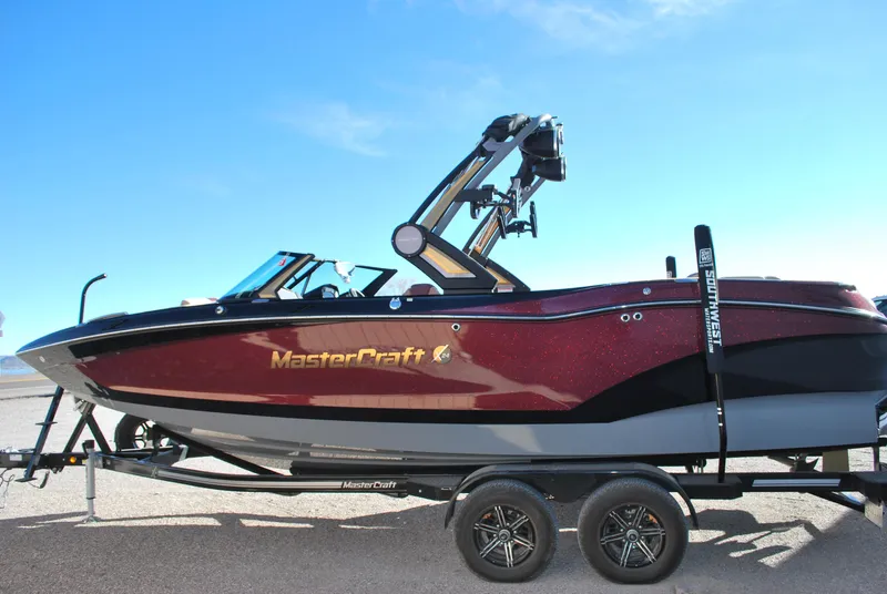 Slide: The Image of 2023 MasterCraft X24 boat on trailer, side view, sunny day. - 2