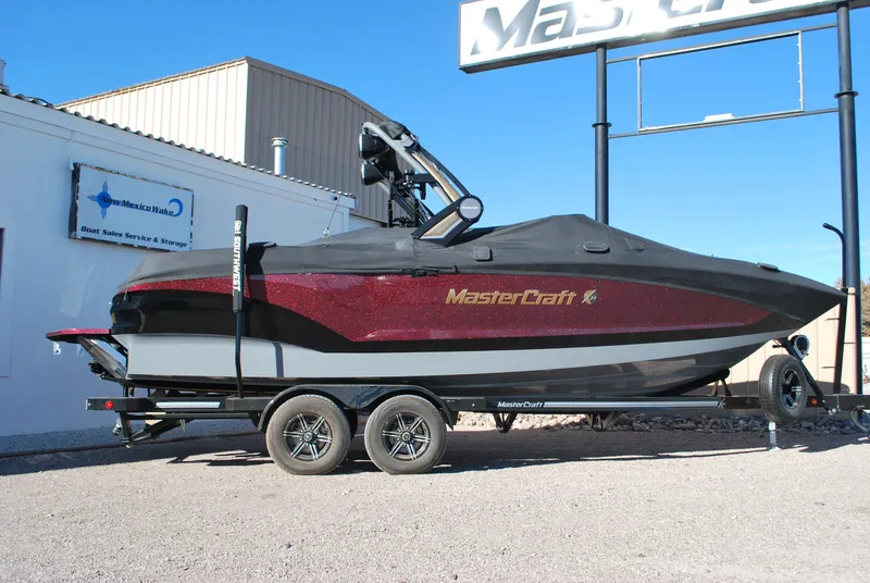 Slide: The Image of 2023 MasterCraft X24 boat on trailer, covered and parked outdoors. - 3