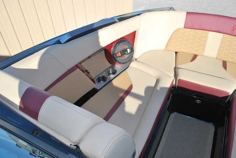 Slide: The Image of 2023 MasterCraft X24 boat interior with beige and maroon seating, cup holders, and speaker. - 7