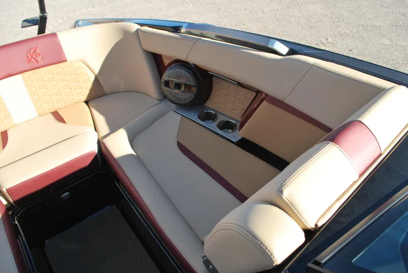 Slide: The Image of 2023 MasterCraft X24 boat interior with beige and red seating, cup holders, and speaker. - 8