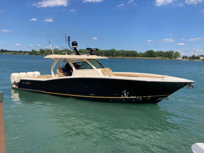 The Image of 2019 Scout 380 LXF boat on calm water under a clear blue sky. - 0