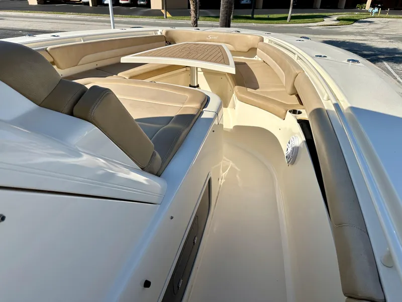 Slide: The Image of 2019 Scout 380 LXF boat interior with beige seating and a wooden table. - 11