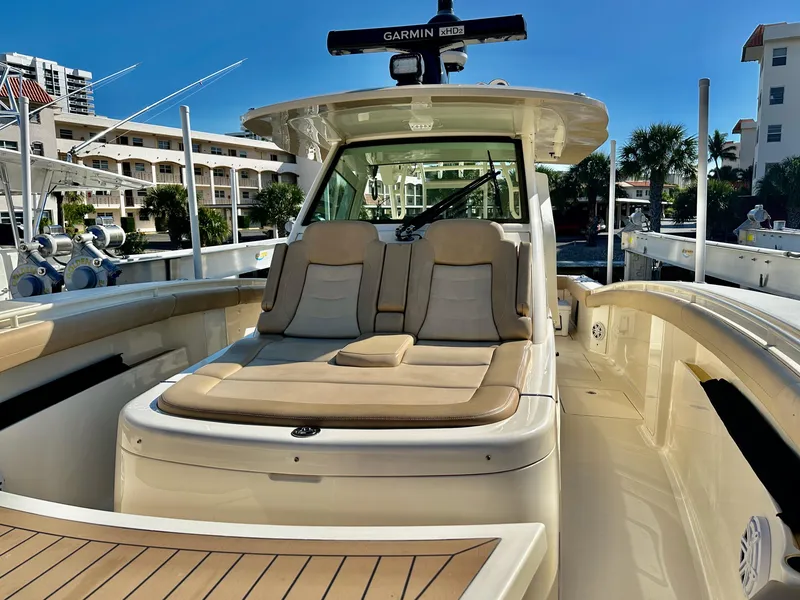 Slide: The Image of 2019 Scout 380 LXF boat with cushioned seating and Garmin radar, docked in a marina. - 12