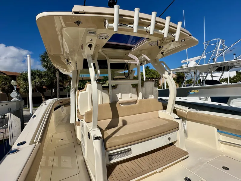 Slide: The Image of 2019 Scout 380 LXF boat interior with seating and rod holders, docked under clear blue sky. - 6