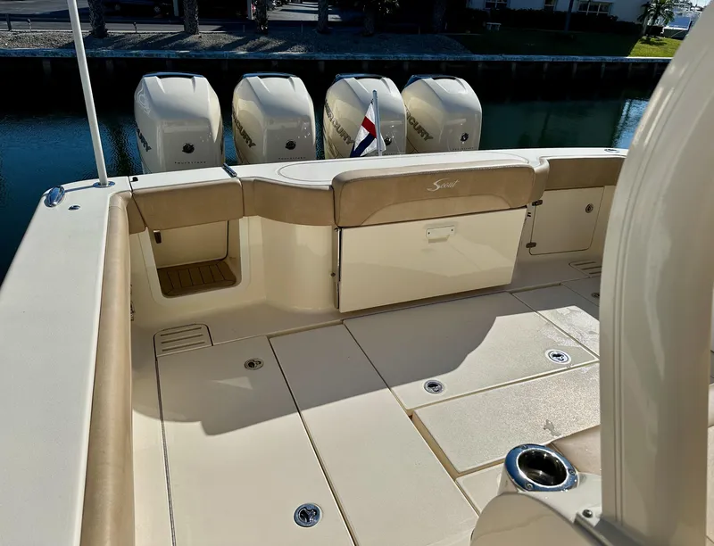 Slide: The Image of 2019 Scout 380 LXF boat deck with four outboard engines, beige seating, and cup holder. - 8