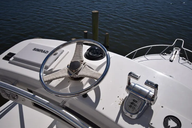 Slide: The Image of Steering wheel and controls of a 2004 Cabo 40 Express boat on water. - 12