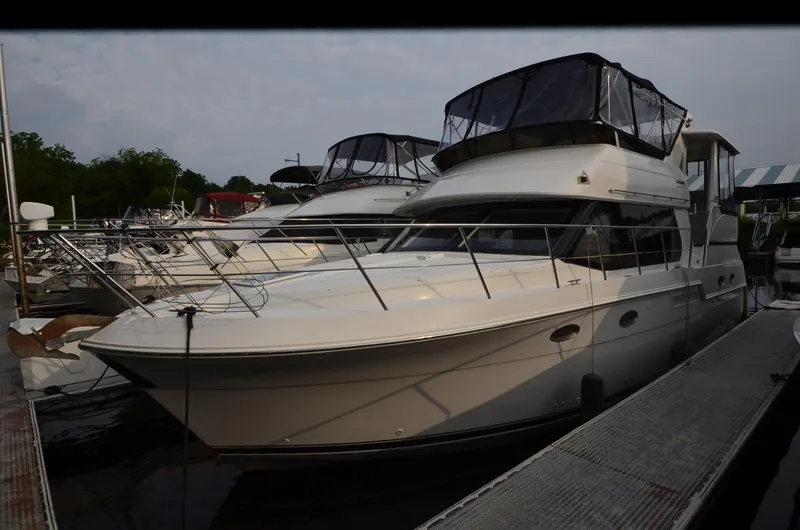 Slide: The Image of 2001 Carver 406 yacht docked at marina, featuring sleek design and spacious upper deck. - 1