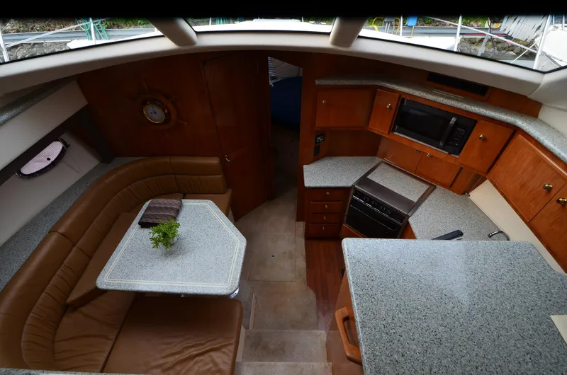 Slide: The Image of Interior of 2001 Carver 406 yacht with kitchen and dining area, featuring wood cabinetry and seating. - 15