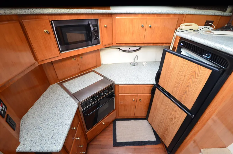 Slide: The Image of 2001 Carver 406 yacht kitchen with microwave, stove, fridge, and wooden cabinetry. - 17