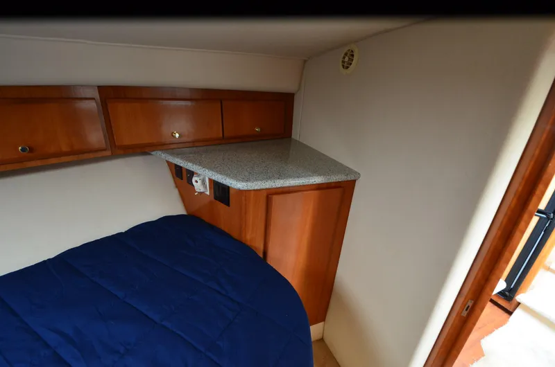Slide: The Image of 2001 Carver 406 cabin interior with wooden cabinets and blue bedding. - 21