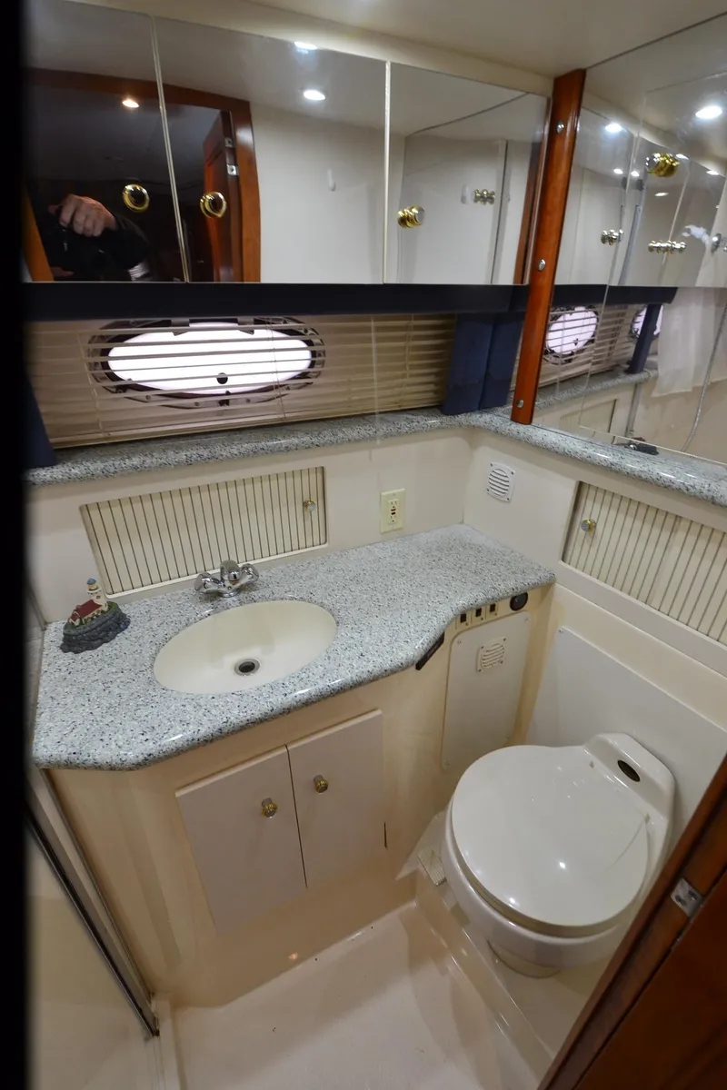 Slide: The Image of 2001 Carver 406 yacht bathroom with sink, toilet, and mirrored cabinets. - 31