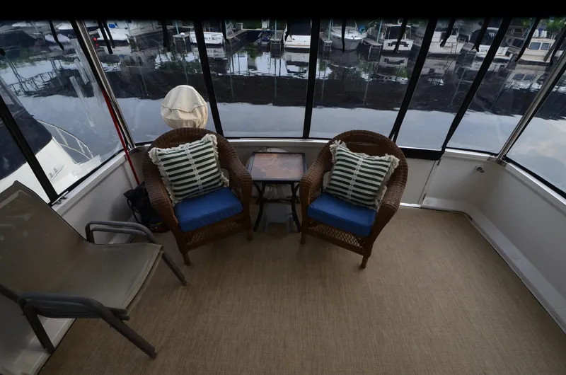 Slide: The Image of Enclosed deck of 2001 Carver 406 yacht with wicker chairs and marina view. - 4