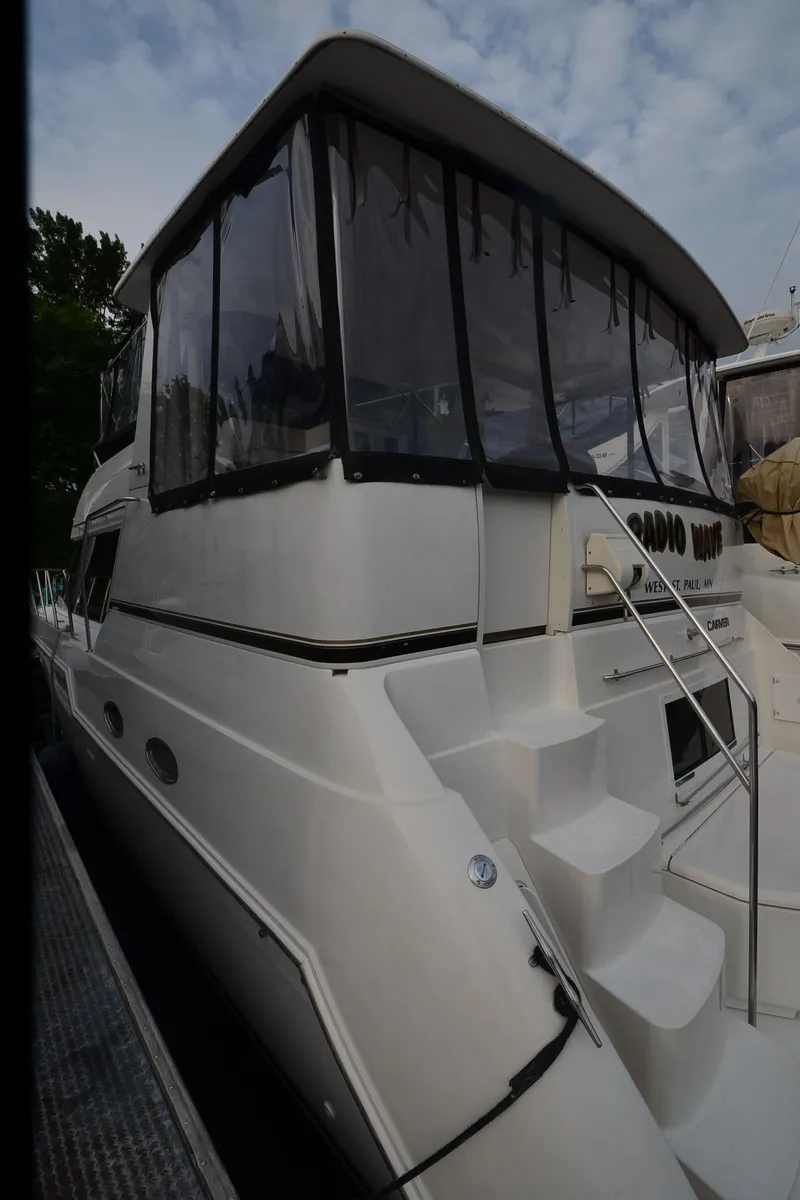 Slide: The Image of 2001 Carver 406 yacht with enclosed upper deck, docked under cloudy sky. - 44