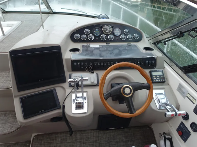 Slide: The Image of 2001 Cruisers Yachts 4270 Express helm with wooden steering wheel and modern navigation instruments. - 10