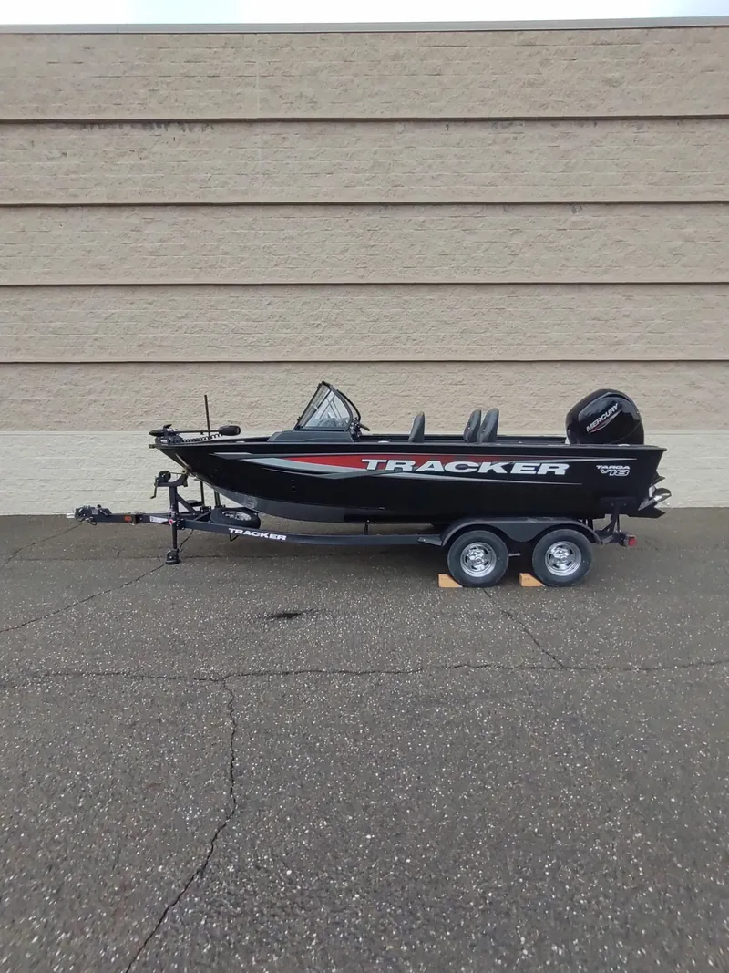 Slide: The Image of 2025 Tracker Targa V-18 Combo boat on trailer, parked against a beige wall. - 6