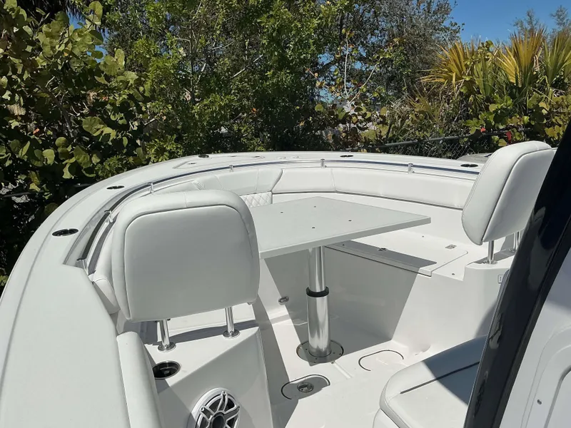 Slide: The Image of 2025 Sportsman 261 Heritage boat interior with seating and table, surrounded by lush greenery. - 14