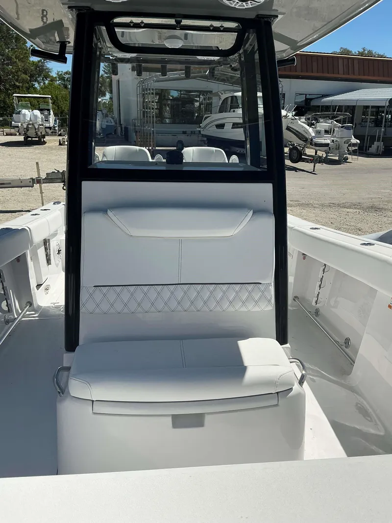 Slide: The Image of 2025 Sportsman 261 Heritage boat interior with white seating and console, docked outdoors. - 17